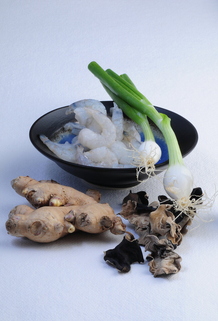 Shrimp in bowl with spring onions, ear mushrooms and ginger on white background