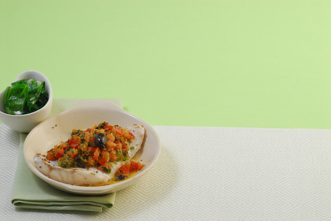 Redfish with olive crust and spinach in serving dish