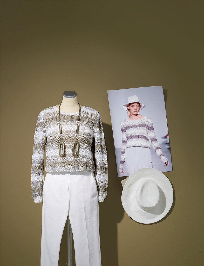 Bright striped knit sweater and white trousers on mannequin