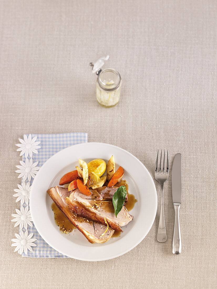 Roasted pork with braised vegetables, sauce and salt on plate