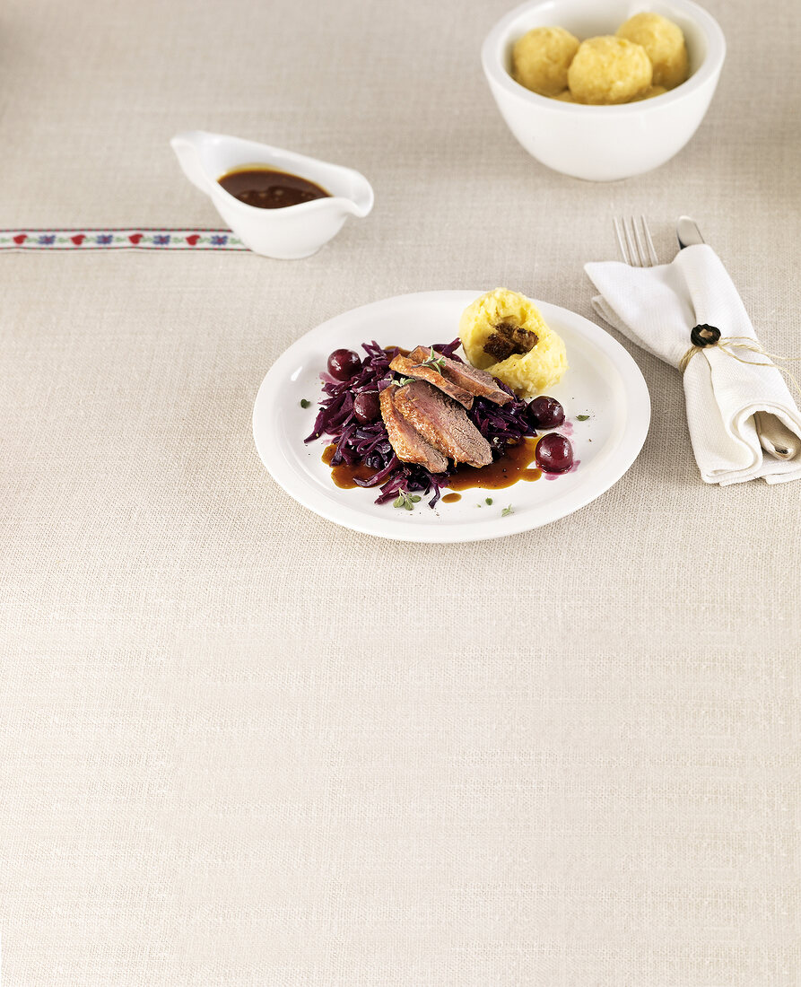 Glazed duck breast garnished with cherry, red cabbage, potato dumpling and sauce