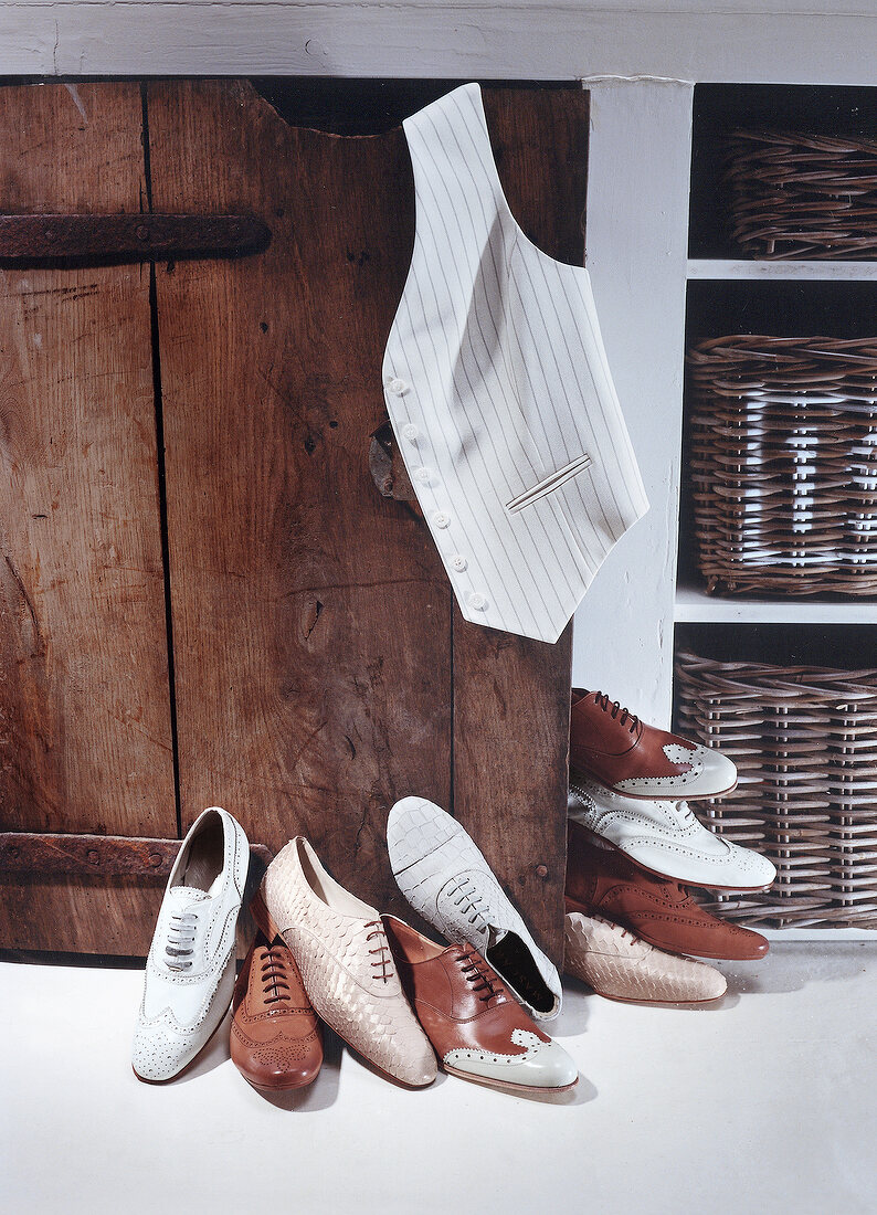 Men's shoes and white vest beside wooden cabinet