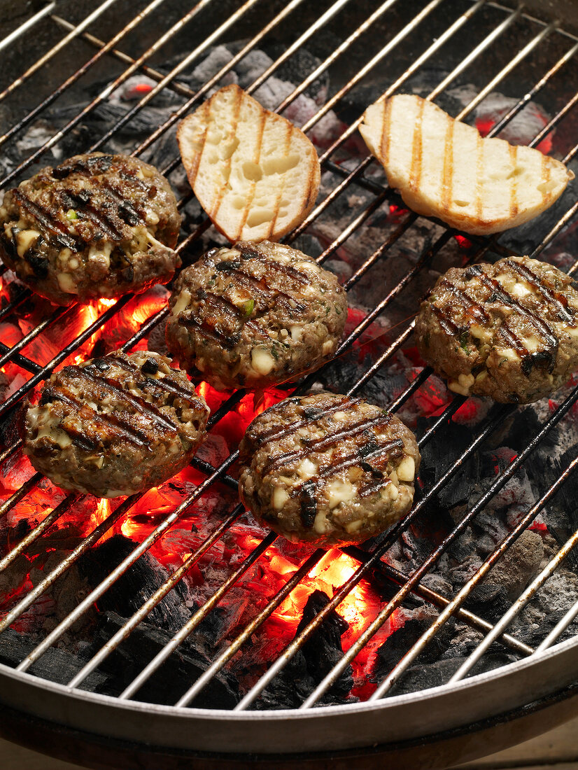 Beef patties and bread on grill, close-up