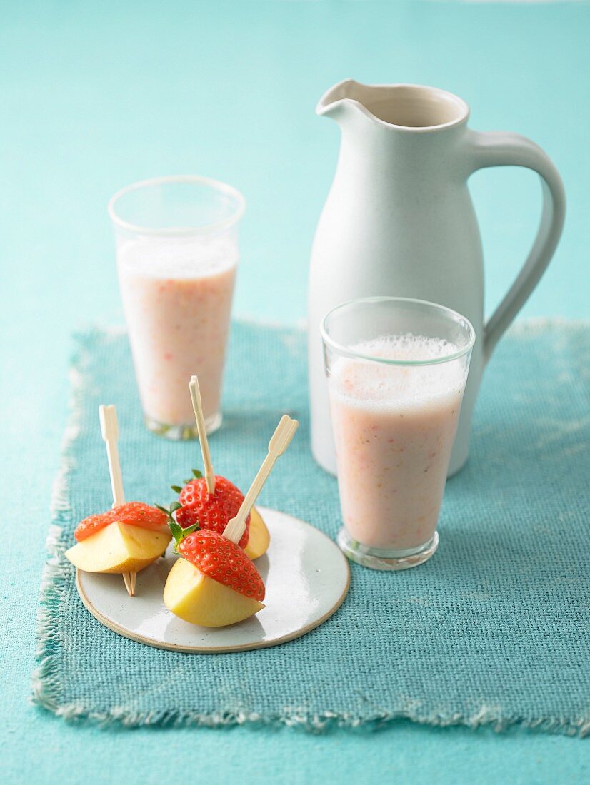 A fruit shake with strawberry and peach skewers