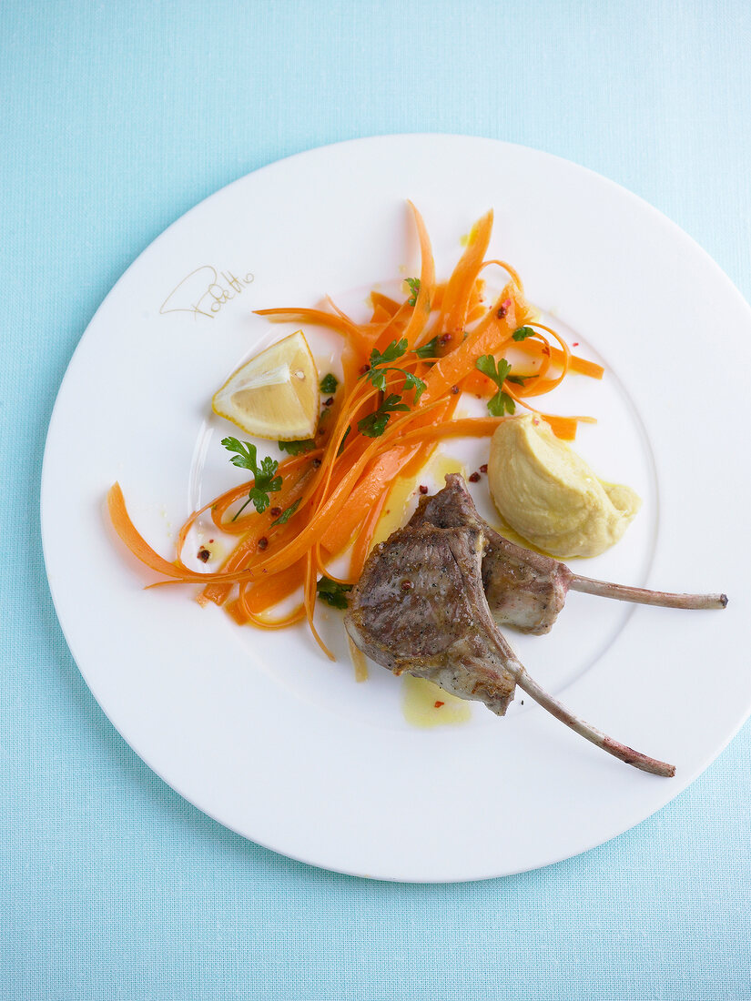 Grilled lamb cutlets with chickpea cream and marinated carrots on plate