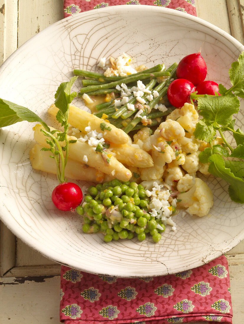 Salad with asparagus, cauliflower, peas, beans and egg on plate