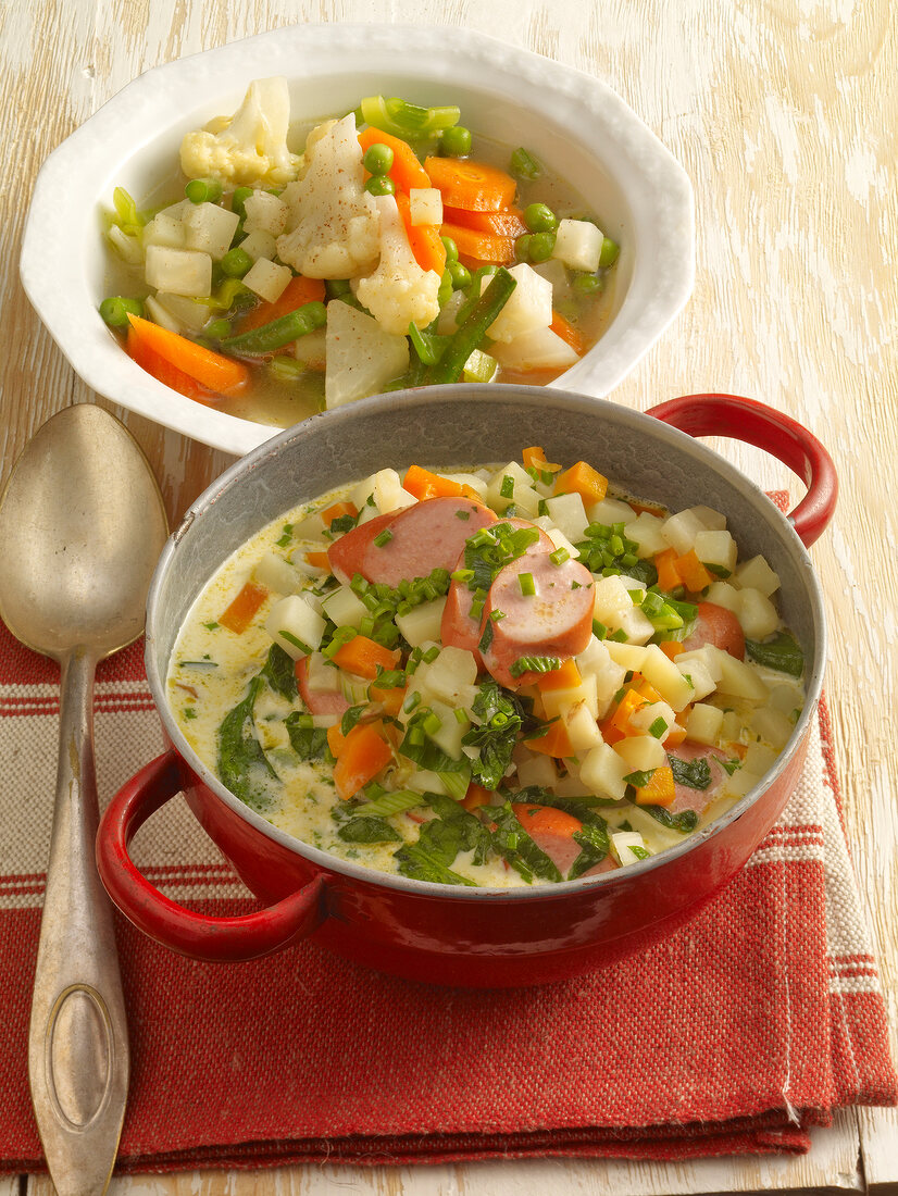 Vegetable soup and green potato soup with sausage in serving dishes