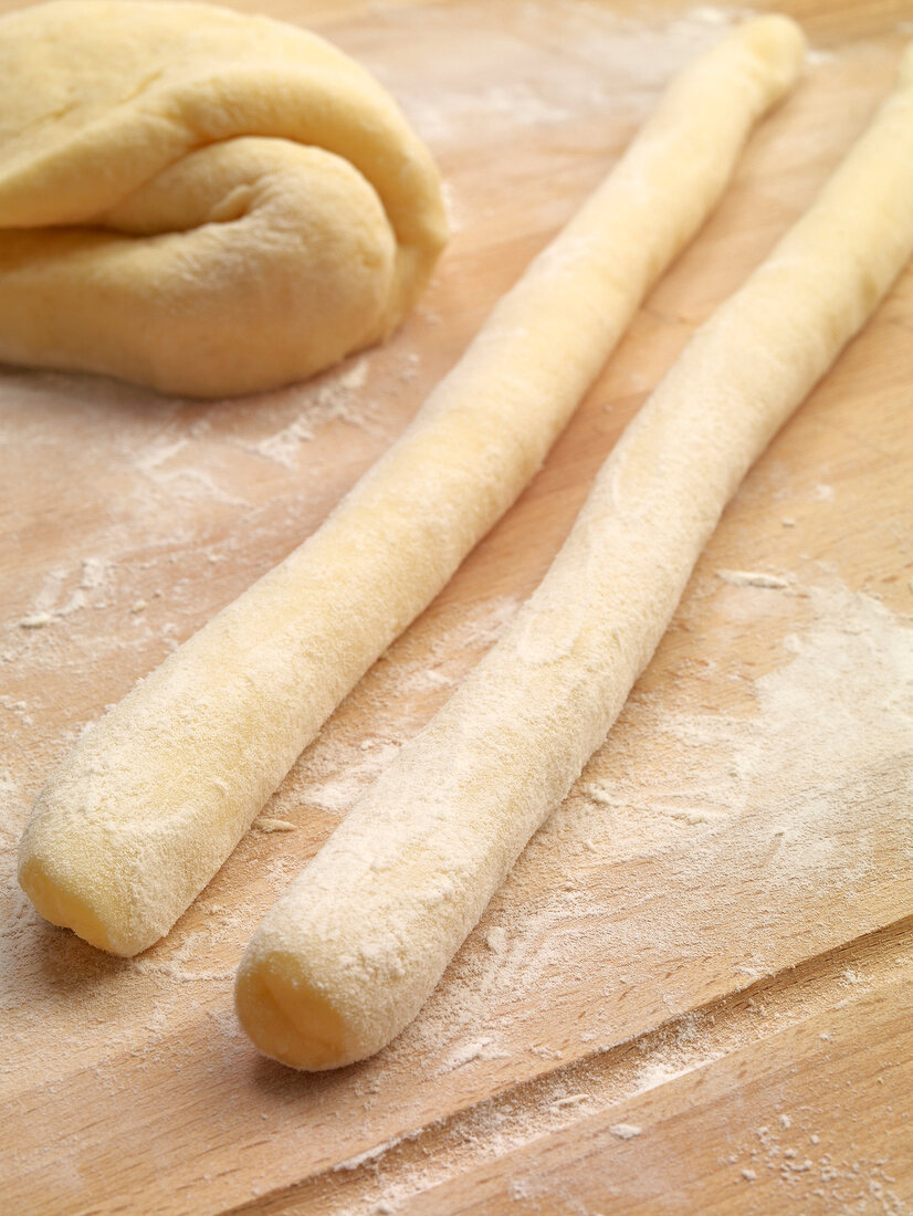 Close-up of potatoes dough rolls in flour while preparing potato noodles, step 2