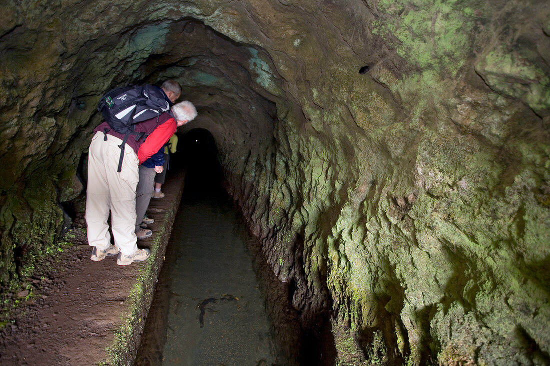 Hikers looking inside tunnel at Levada Tour in Madeira, Portugal