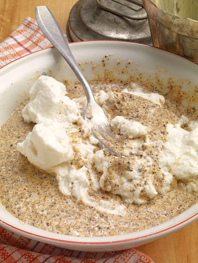 Egg white and batter being mixed in bowl while preparing chocolate cake, step 1