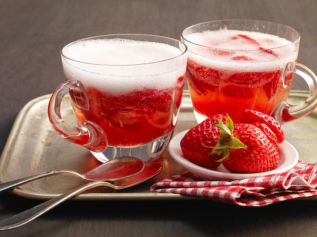 Two glasses of strawberry punch with ice cubes and fresh strawberries