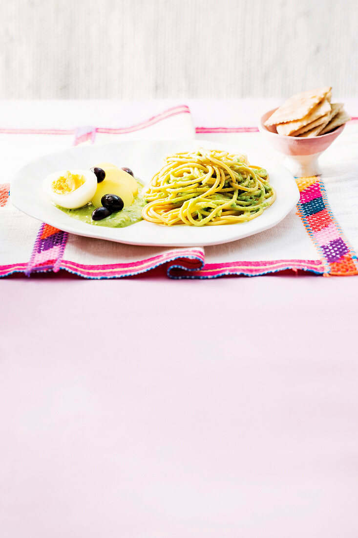 Spaghetti with green chilli, fresh cheese sauce, egg and olives on plate