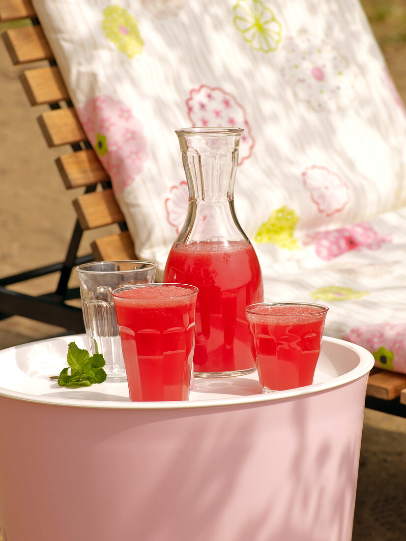 Karaffe und Gläser mit Melonenlimo- nade, rot