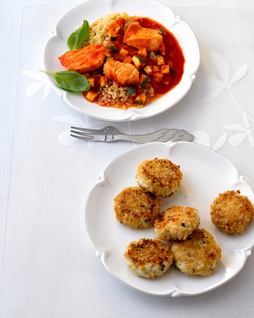 Fish cakes and fish in tomato sauce with rice on plates