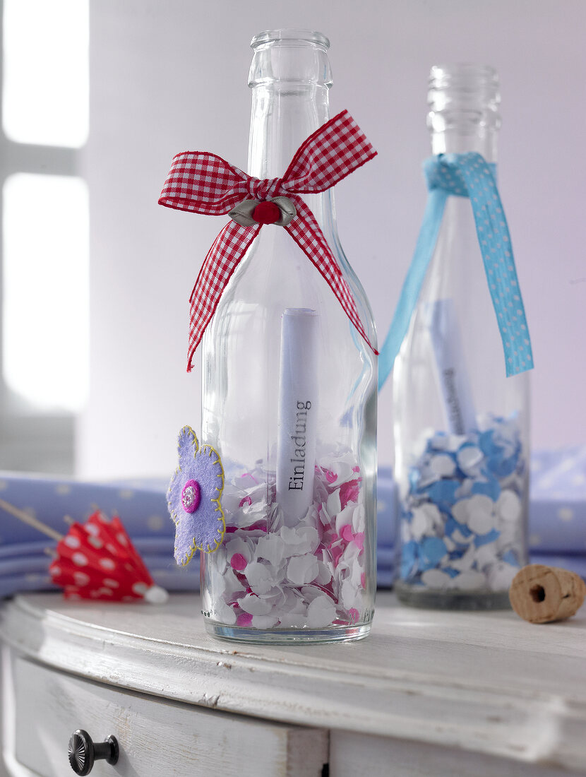 Confetti in bottles decorated with tied bow for invitation