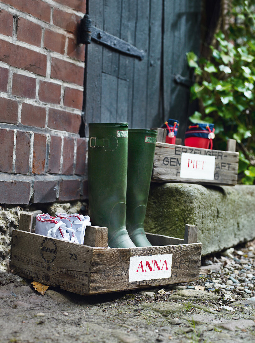 Holzkiste mit Schuhen und Namens- schild