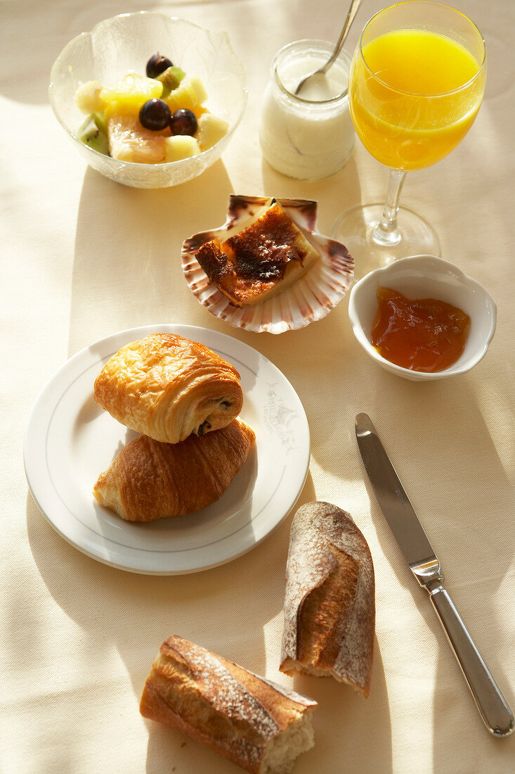 Croissants, jam, juice and fruits on breakfast table