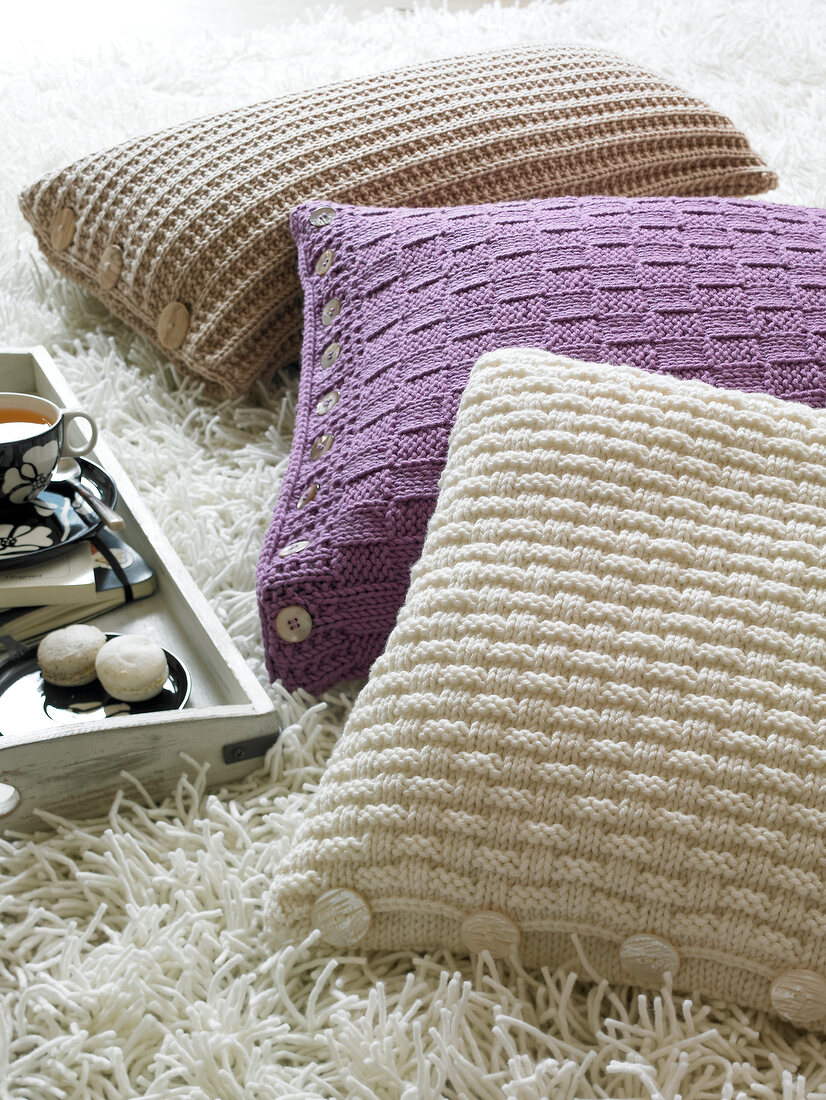 Close-up of three knitted cushions on carpet