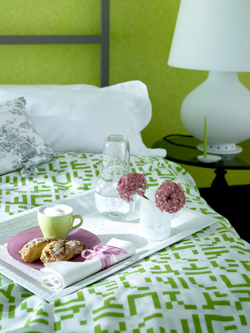 Breakfast on tray being served on bed with green and white linens