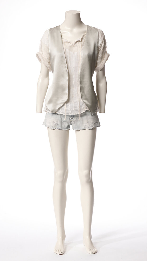 Satin vest over white blouse and blue shorts on mannequin against white background