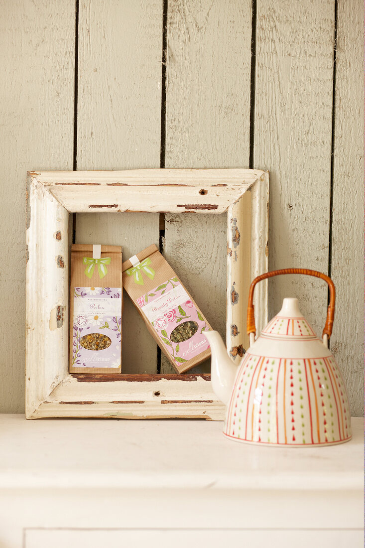 Two packets of teas in picture frame with tea pot