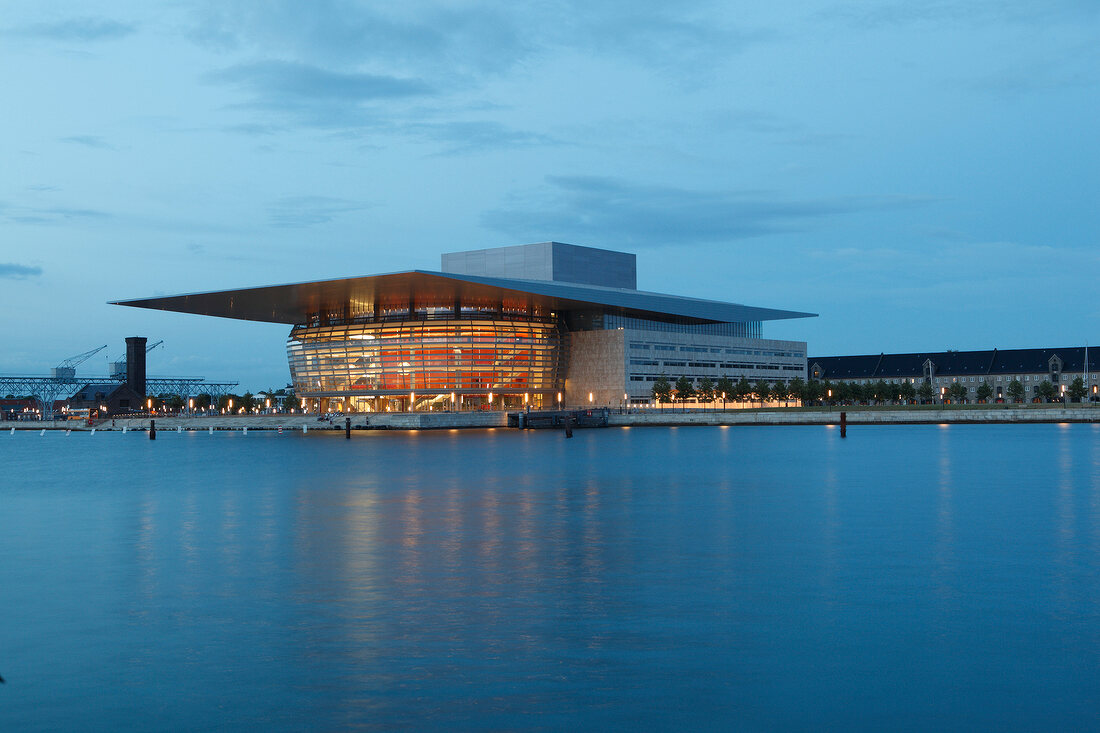 Illuminated opera house along river in Copenhagen, Denmark