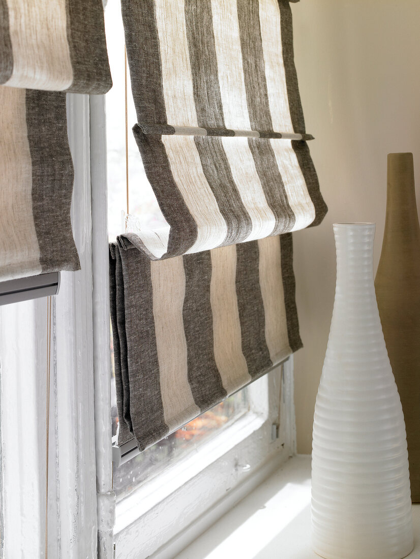 Close-up of brown and biege striped roman shades on window