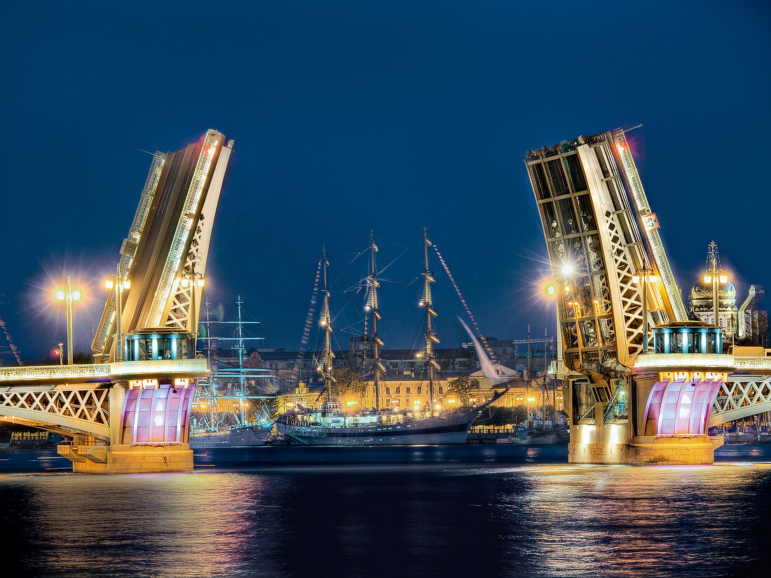 Illuminated bridge pulled up and ship in Neva River at night in St. Petersburg, Russia