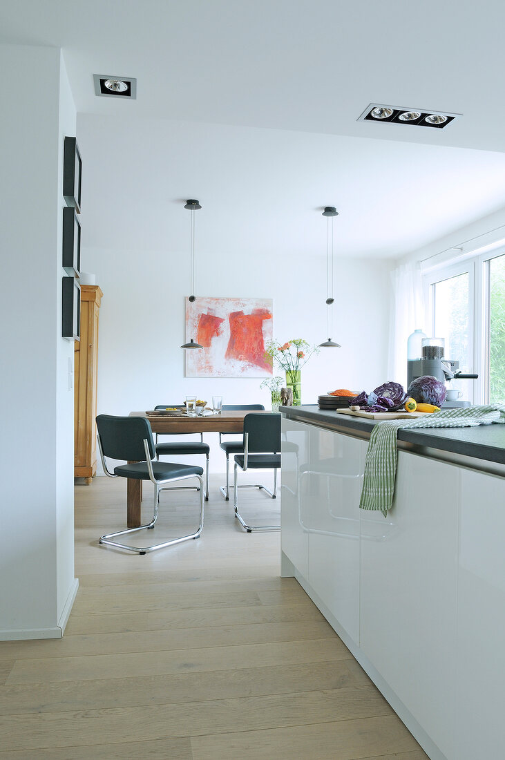 Kitchen countertop, dining table and chairs in front of painting on wall in dining room