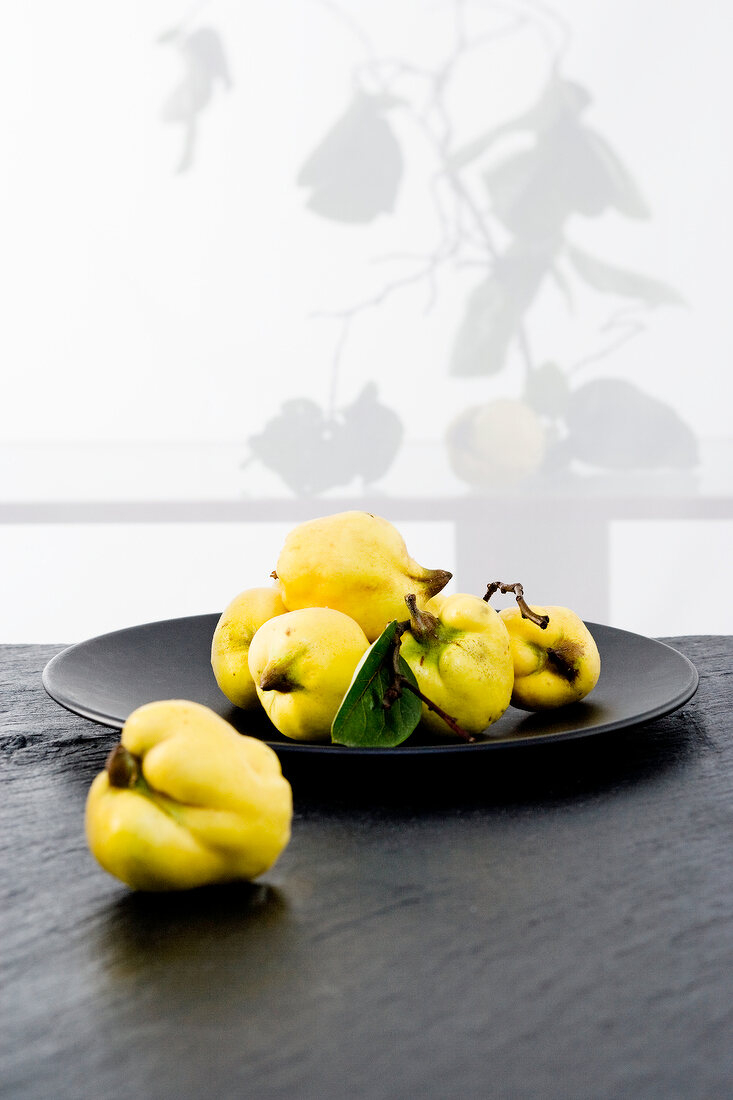 Fresh quinces on black plate