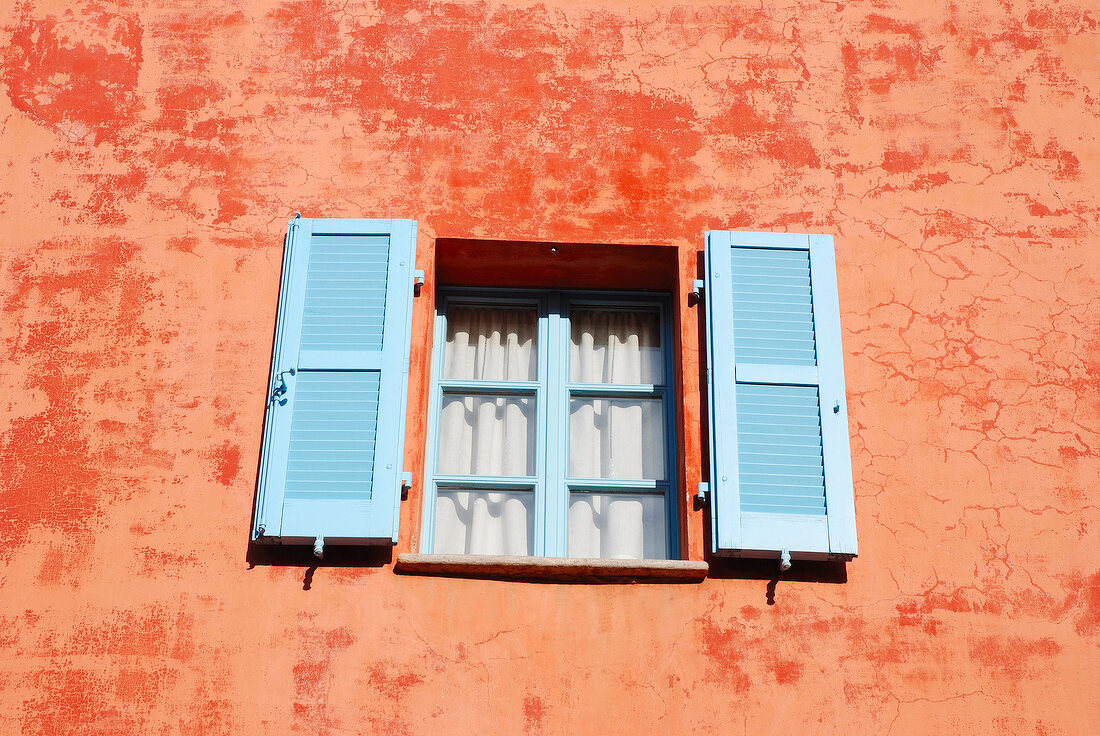 Tessin: Haus, Fassade orange, Fen- ster, Fensterläden blau.
