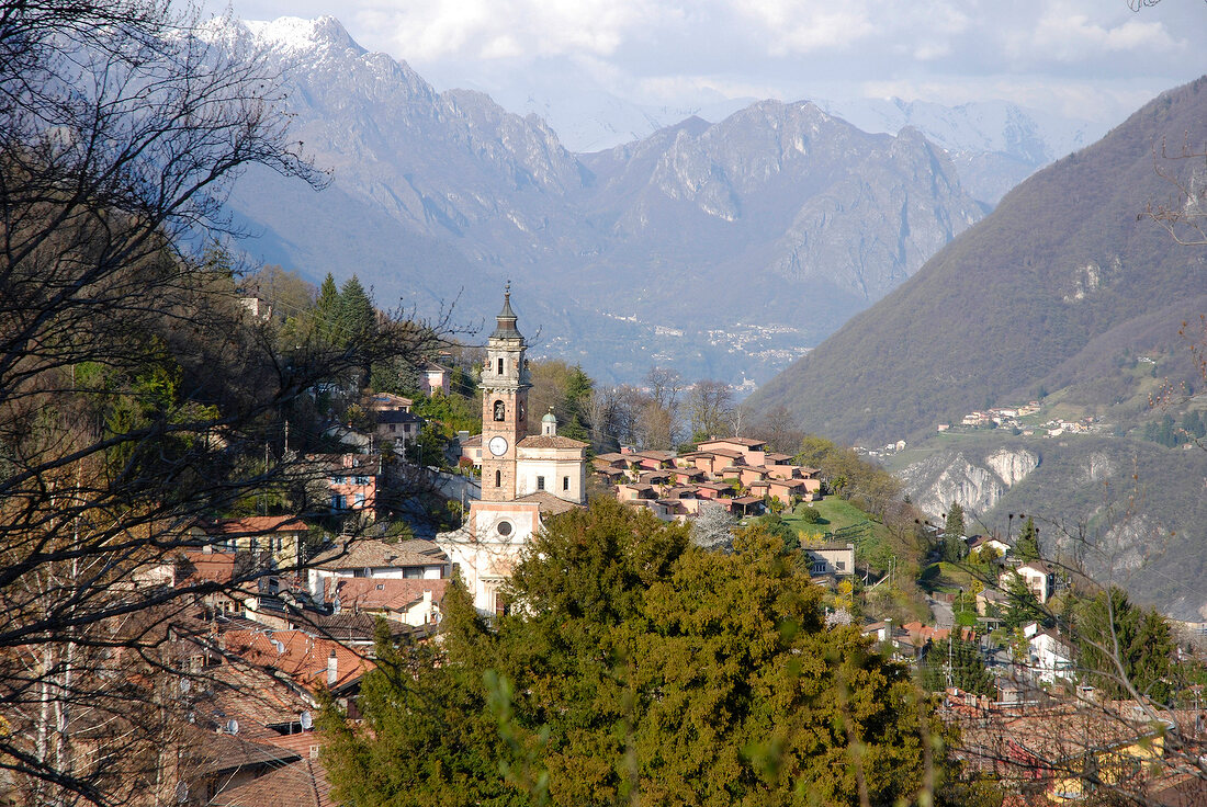 View of cityscape of Ticino with houses, church and mountain range, Switzerland