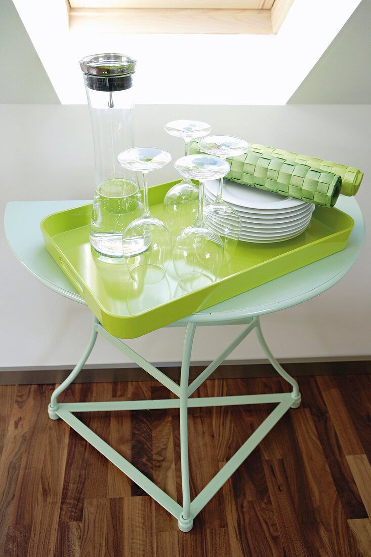 Stack of plates, wine glasses, decanter on green tray