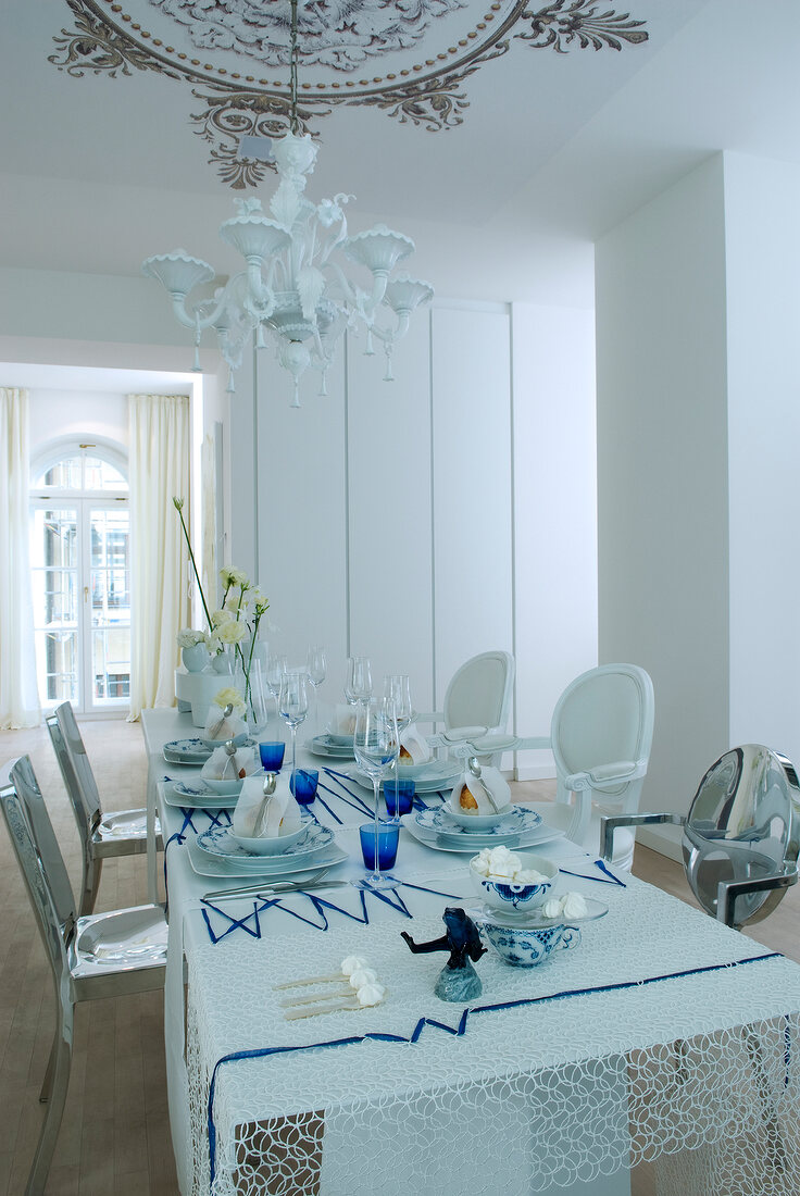 View of white dining room with covered set table and chandelier