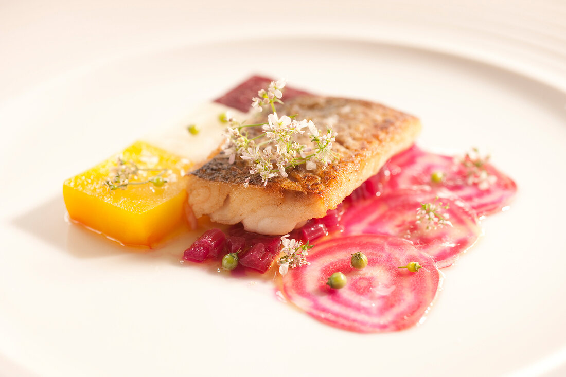 Close-up of whitefish fillet with colourful dressing on plate