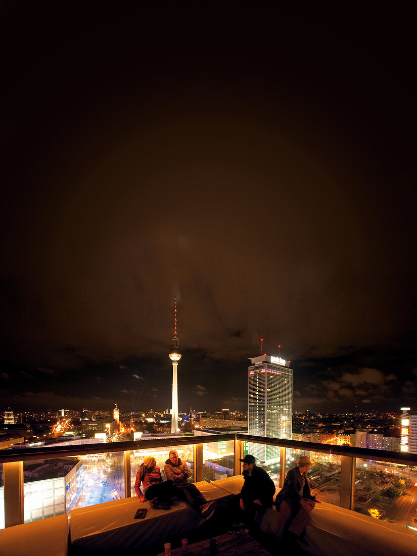 People on Club Week End rooftop and view of cityscape at night