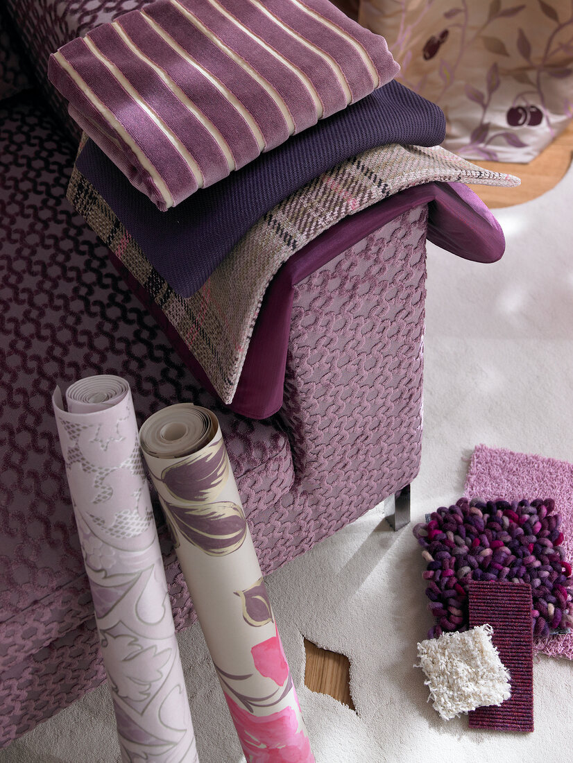 Variety of fabrics in purple colour with wallpaper on side