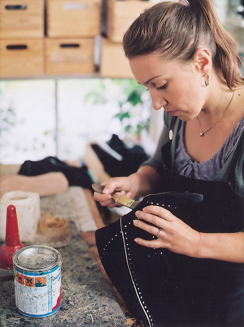 Shoemaker Anja Hoffmann applying glue on shoe sole