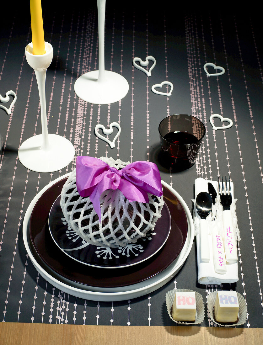Table with candles, cutlery, plate, hearts and ribbons