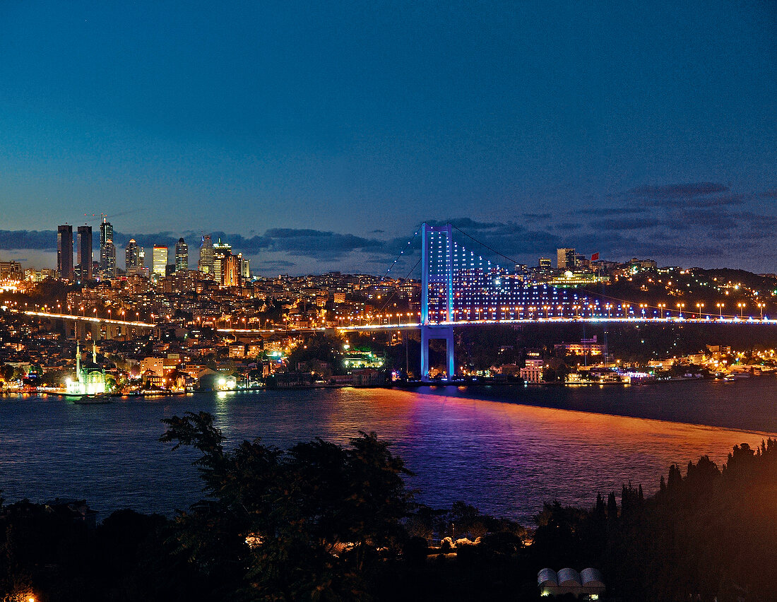 View of illuminated Bosphorus Bridge and cityscape at night