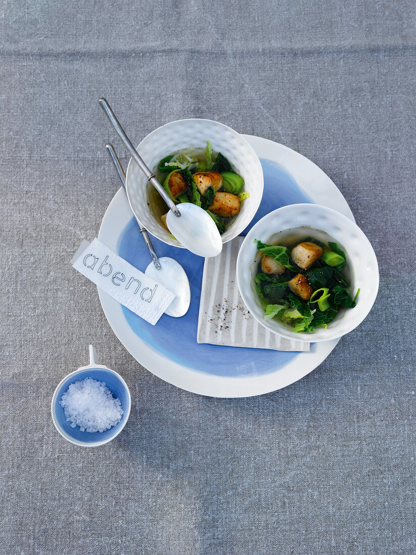 Two soup bowls with chicken stew on plate, overhead view