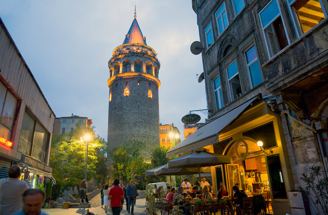 View of Galata Tower Building and people walking in alley at dusk, Istanbul, Turkey