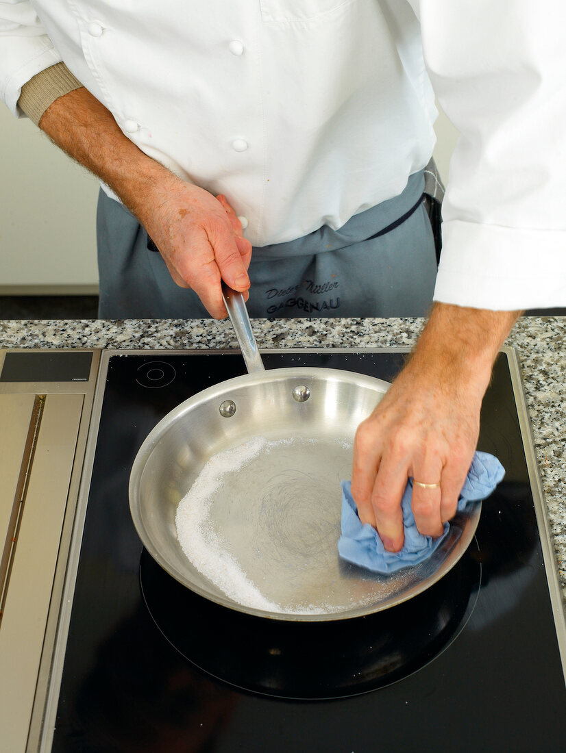 Man's hands wiping pan with cloth