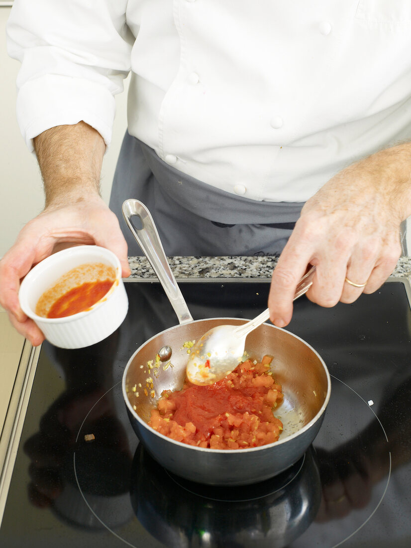 Man's hands adding diced tomato stew in saucepan