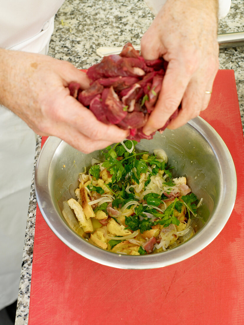 Close-up of man's hands adding meat in bowl