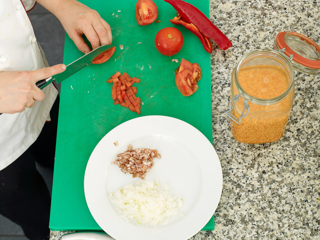 Man's hand chopping tomatoes with knife on cutting board