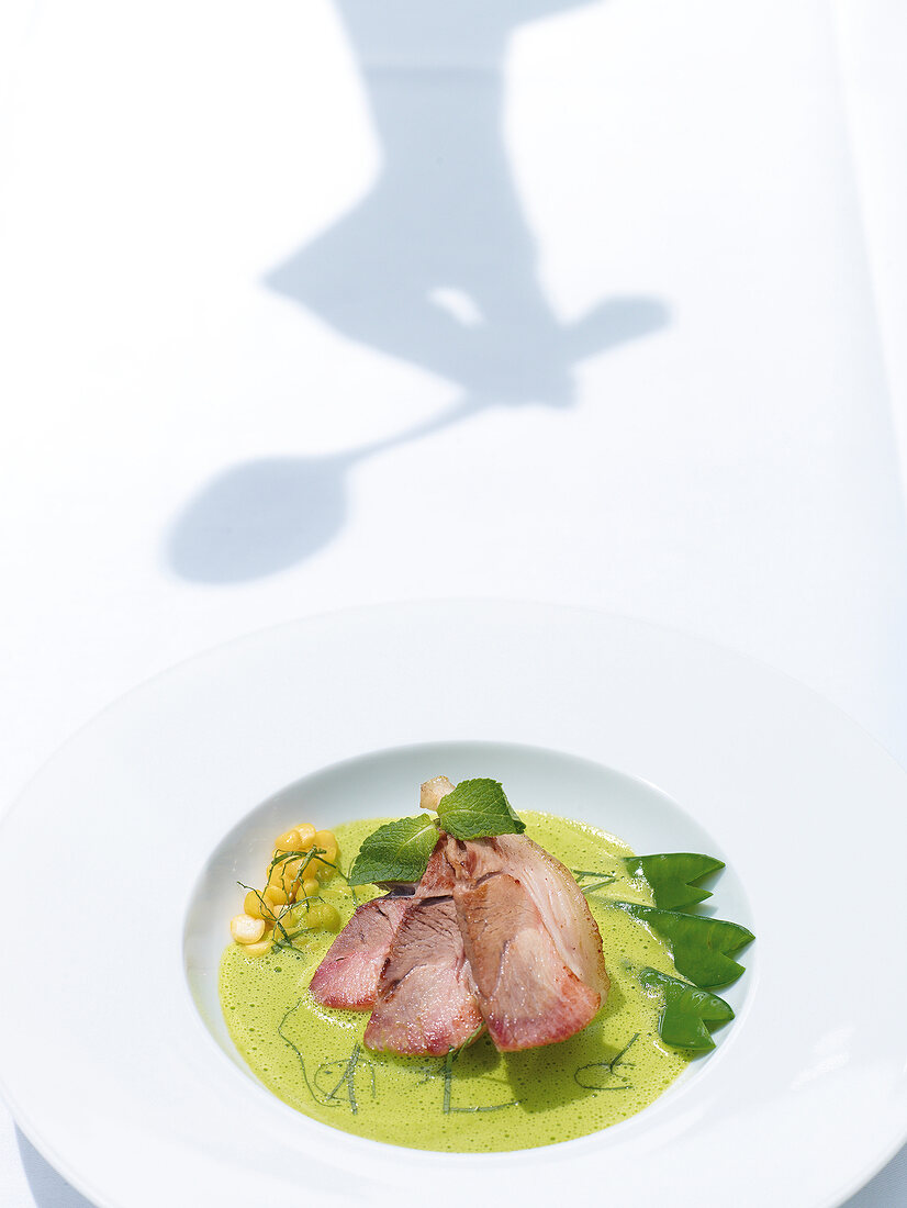 Pea soup with knuckle of pork and mint on dish