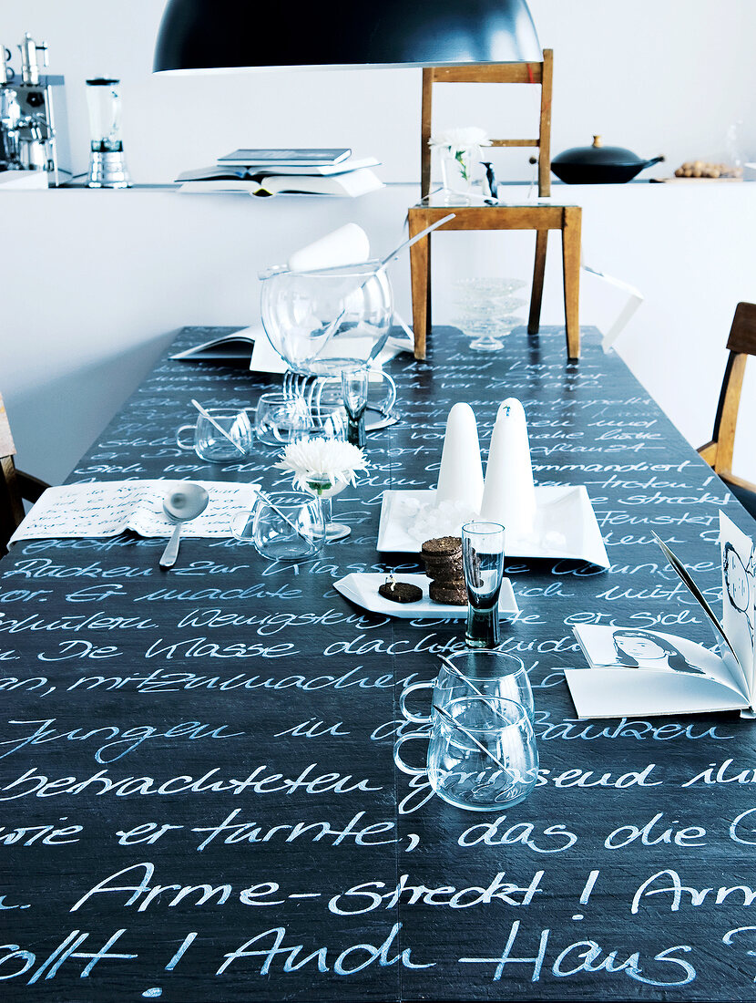 Black and white dining table with epigraphy and glasses, cutlery and chair on it