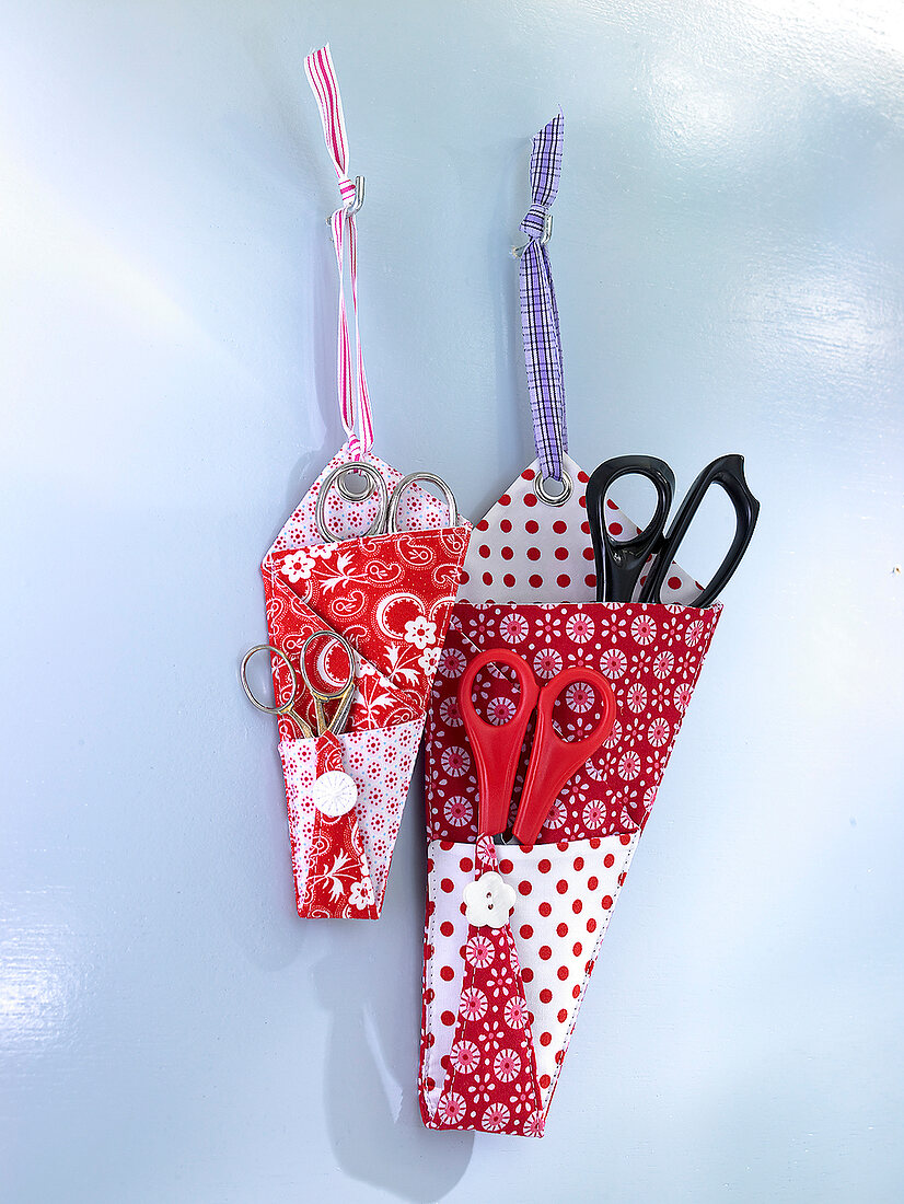 Red and white fabric pockets for scissors hanging on wall