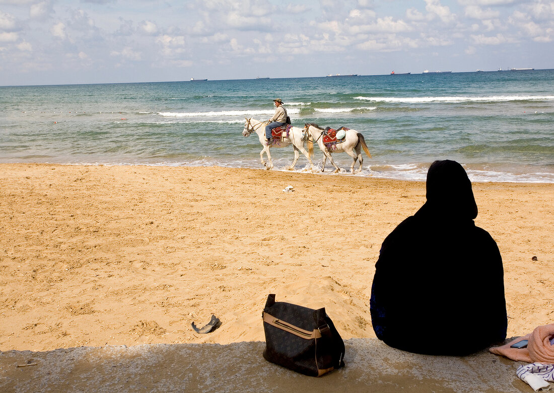 Woman watching man riding horse on beach during summer vacation at Kilyos, Turkey
